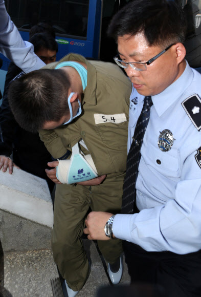23일 울산지방법원 앞에서 울산의 자매살인범 김홍일(왼쪽)이 구치소 직원의 호송을 받으며 재판을 받기위해 법원 청사 안으로 들어가고 있다. 연합뉴스