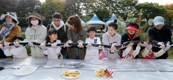 28일 오전 서울 송파구 성내천에서 열린 아동권리축제에 참가한 어린이들과 주민들이 36.5미터 대형 김밥을 만들고 있다.  연합뉴스