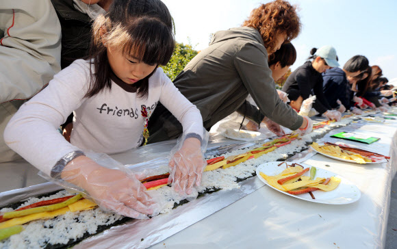 28일 오전 서울 송파구 성내천에서 열린 아동권리축제에 참가한 어린이들과 주민들이 36.5미터 대형 김밥을 만들고 있다.  연합뉴스