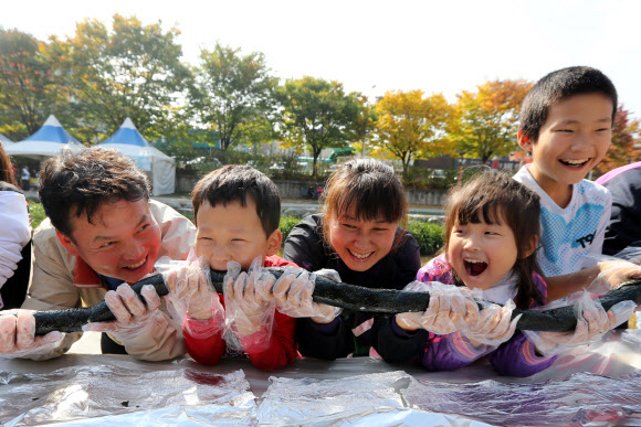 28일 오전 서울 송파구 성내천에서 열린 아동권리축제에 참가한 어린이들과 주민들이 36.5미터 대형 김밥을 만들고 있다.  연합뉴스
