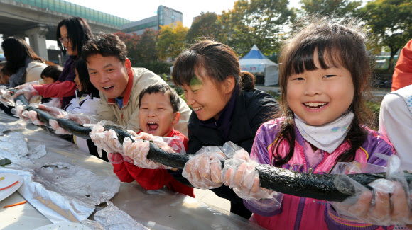 28일 오전 서울 송파구 성내천에서 열린 아동권리축제에 참가한 어린이들과 주민들이 36.5미터 대형 김밥을 만들고 있다.  연합뉴스