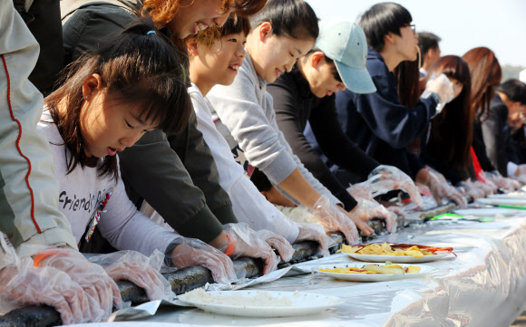 28일 오전 서울 송파구 성내천에서 열린 아동권리축제에 참가한 어린이들과 주민들이 36.5미터 대형 김밥을 만들고 있다.  연합뉴스