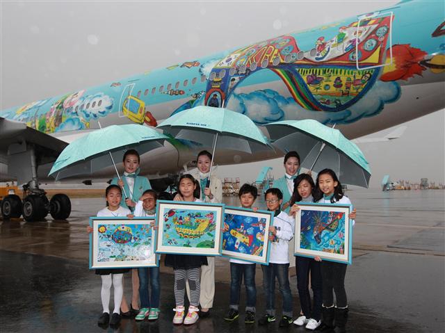 지난 27일 서울 김포공항 국내선 청사에서 열린 ‘제4회 내가 그린 예쁜 비행기’ 사생대회 시상식을 마치고 대한항공 승무원들과 수상 어린이들이 A330 래핑 항공기 앞에서 기념 촬영을 하고 있다.  대한항공 제공