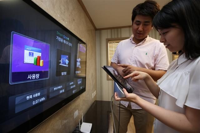 제주 스마트그리드 실증단지에서 직원들이 스마트 TV와 태블릿 PC를 통해 가정 내 전력 사용정보를 확인하고 있다. LG그룹 제공