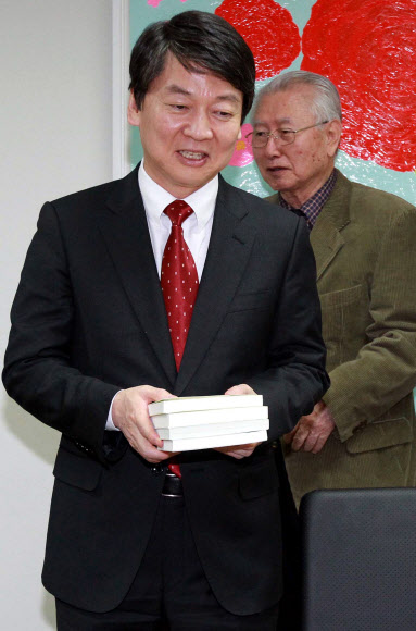 안철수 대선후보가 13일 오후 서울 종로구 신교동 푸르메재단을 방문, 재단이사장인 김성수 대한성공회 주교와 면담하기에 앞서 책을 선물받은 뒤 자리에 앉고 있다.  연합뉴스