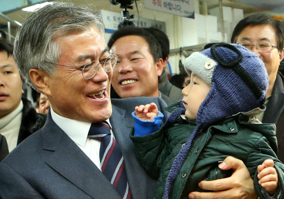 민주통합당 문재인 대선후보가 14일 오후 부산 남포동 자갈치 시장을 방문, 장을 보러 나온 부산 시민들과 인사를 나누던 중 어린이를 안고 밝은 표정을 짓고 있다. 연합뉴스