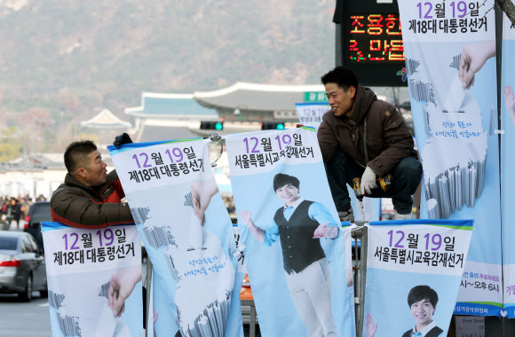 서울특별시선거관리위원회 직원들이 25일 오전 서울 종로구 세종로에서 18대 대통령선거와 시교육감재선거 참여 유도를 위한 가로등 배너를 설치하고 있다.  연합뉴스