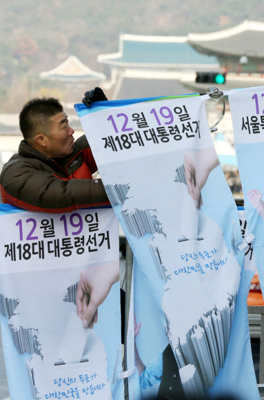 서울특별시선거관리위원회 직원들이 25일 오전 서울 종로구 세종로에서 18대 대통령선거와 시교육감재선거 참여 유도를 위한 가로등 배너를 설치하고 있다.  연합뉴스