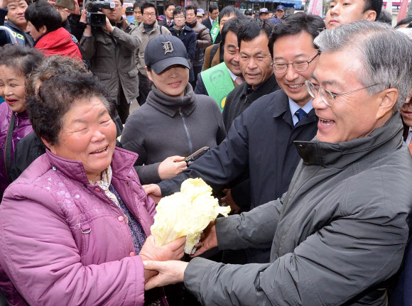 민주통합당 문재인 대선 후보가 29일 오전 전남 여수시 서교동 서시장을 방문, 손에 배추를 든 상인과 인사하고 있다.  연합뉴스