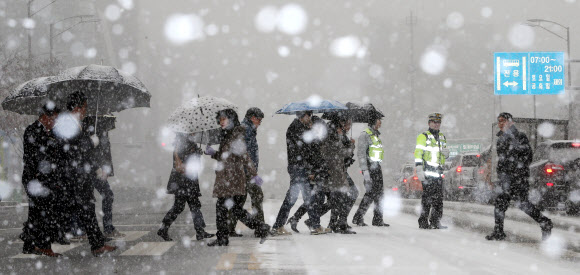 서울지역에 눈이 내린 5일 서울 강남구 삼성동에서 시민들이 횡단보도를 건너고 있다. 연합뉴스