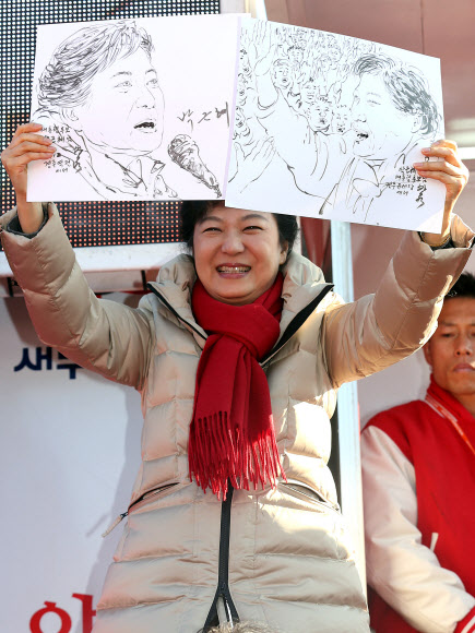 새누리당 박근혜 대선후보가 12일 오후 경북 경주 성동동 경주역광장에서 열린 집중유세에서 한 화가가 즉석에서 그린 박 후보의 유세 장면 그림을 받아 들어보이고 있다. 박 후보는 이날 ‘텃밭’인 대구ㆍ경북(TK)과 울산, 충청을 두루 훑는 전국 순회유세에 나섰다. 연합뉴스