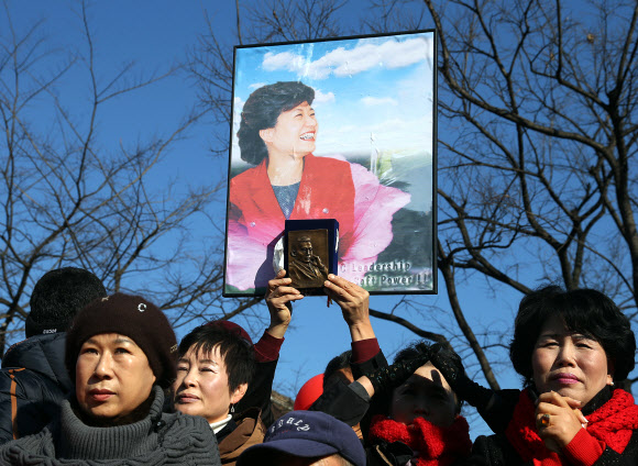 12일 오후 경북 경주 성동동 경주역광장에서 열린 새누리당 박근혜 대선후보의 집중유세에서 한 지지자가 박 후보의 사진과 박정희 전 대통령의 동판을 들고 있다. 박 후보는 이날 ‘텃밭’인 대구ㆍ경북(TK)과 울산, 충청을 두루 훑는 전국 순회유세에 나섰다. 연합뉴스