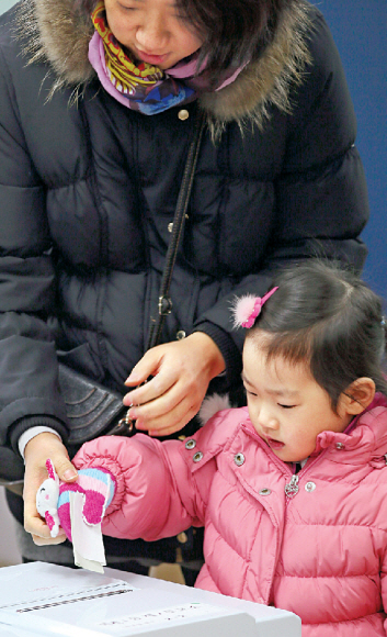 미래를 위하여   서울 송파구 마천1동 주민센터에 마련된 투표장에서 한 어린이가 엄마의 기표용지를 받아 대신 투표함에 넣고 있다.   연합뉴스