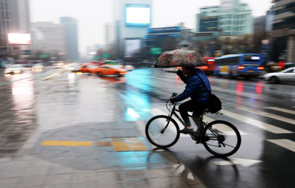 전국이 흐리고 눈 또는 비가 내린 21일 오전 서울 광화문 사거리에서 자전거를 탄 한 시민이 건널목을 건너고 있다. 연합뉴스