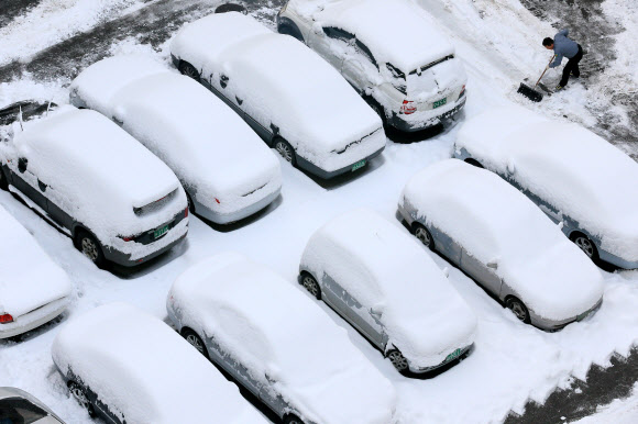 서울지역에 16.5㎝의 폭설이 쏟아진 4일 오전 서울 성동구 응봉동의 한 아파트 주차장에서 주민들이 쌓인 눈을 치우고 있다. 연합뉴스