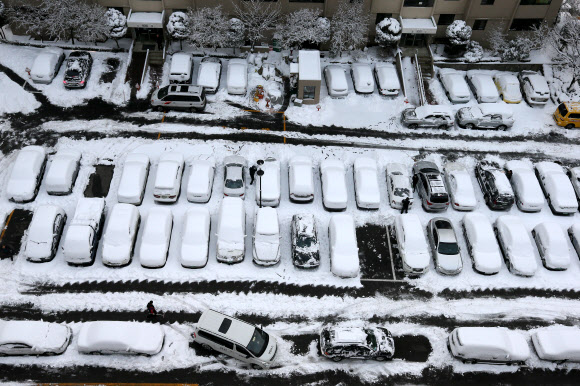 서울지역에 16.5㎝의 폭설이 쏟아진 4일 오전 서울 성동구 응봉동의 한 아파트 주차장에서 주민들이 차에 쌓인 눈을 치우고 있다.  연합뉴스