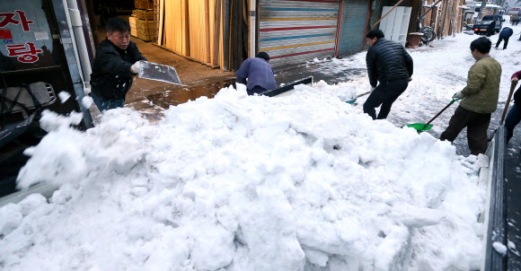 서울지역에 16.5㎝의 폭설이 쏟아진 4일 오전 서울 중구 을지로 중부시장에서 상인들이 트럭을 동원해 도로에 쌓인 눈을 치우고 있다.  연합뉴스