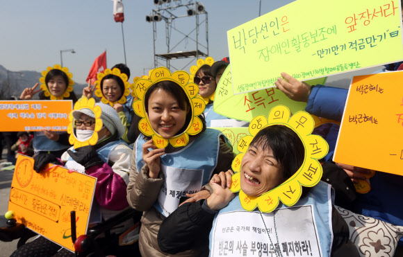 26일 오후 서울 광화문광장에서 열린 제9회 전국장애인대회에서 참석자들이 구호가 적힌 팻말을 들고 밝게 웃고 있다. 연합뉴스