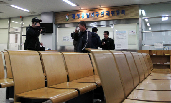 4일 오전 경기도 파주시 경의선 남북출입사무소(CIQ)에서 텅빈 의자 뒤로 몇몇 근로자들이 통행이 재개되기를 기다리며 서로 대화를 나누고 있다. 연합뉴스