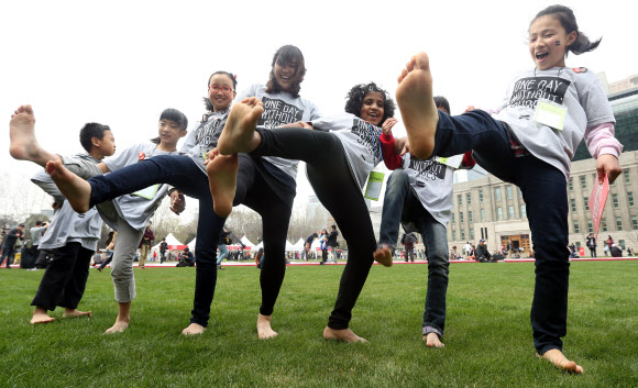 16일 오후 서울광장에서 열린 ‘신발 없는 하루’ 캠페인에서 어린이들이 맨발을 들어올리고 있다. ‘신발 없는 하루’는 신발을 하루 동안 벗고 일상을 보내는 날로 신발이 어린이들에게 줄 수 있는 영향력을 알리고 고객이 신발 한 켤레를 구매할 때마다 맨발의 어린이에게 신발 한 켤레를 전달하는 캠페인이다.  연합뉴스