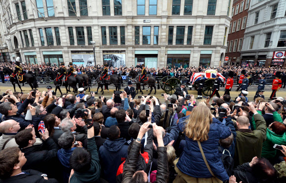 17일(현지시간) 마거릿 대처 전 영국 총리의 관이 대포를 장착한 4륜 마차에 실려 지나가자 고인의 마지막 모습을 보기 위해 나온 런던 시민들이 휴대전화로 촬영하고 있다. 런던 AFP 연합뉴스