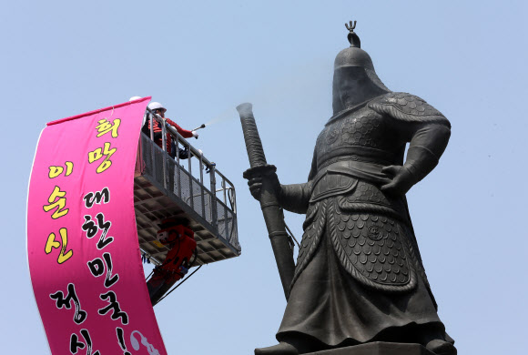 18일 오후 서울 세종로 이순신 장군 동상 앞에서 열린 ‘이순신 장군 동상 친수식’에서 최창식 중구청장(왼쪽)과 복기왕 아산시장이 동상을 세척하고 있다.