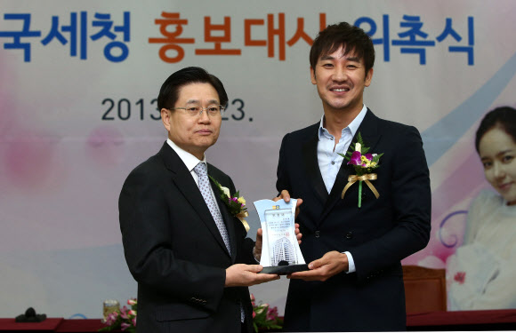 23일 오전 서울 종로구 수송동 국세청 회의실에서 열린 ‘2013 국세청 홍보대사 위촉식’에서 김덕중 청장(왼쪽)이 배우 엄태웅에게 위촉패를 전달하고 있다. 연합뉴스