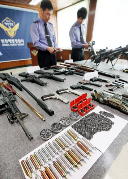 인천 해양경찰서는 해외에서 불법 총기를 밀반입해 국내에 유통한 혐의(총포도검화약류 등 단속법위반)로 A(29)씨 등 4명을 검거했다고 24일 밝혔다. 이들은 지난해 10월부터 최근까지 중국, 홍콩 등 해외에서 밀반입한 공기소총, 모의총기 등 불법 총기류 31점을 인터넷 쇼핑몰에 판매한 혐의를 받고 있다. 사진은 이날 경찰이 압수한 불법 총기를 살펴보는 모습.  연합뉴스