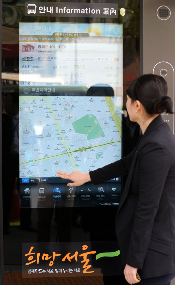 서울시가 내년 3월까지 가로변 버스정류소를 최첨단 시설을 갖춘 정류소로 개선하기로 한 가운데 24일 서울시 관계자가 시범운영 중인 광화문 정류소에서 버스노선을 검색하고 있다.  연합뉴스