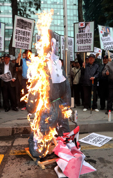 25일 오후 서울 종로구 중학동 일본대사관 앞에서 대한어버이연합과 보수국민연합 회원들이 일본 역사왜곡과 신사참배 규탄 기자회견을 가진 뒤 아베 총리 이름을 붙인 인형에 불을 지르고 있다.  연합뉴스