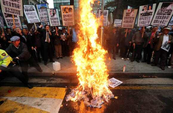 25일 오후 서울 종로구 중학동 일본대사관 앞에서 대한어버이연합과 보수국민연합 회원들이 일본 역사왜곡과 신사참배 규탄 기자회견을 가진 뒤 아베 총리 이름을 붙인 인형에 불을 지르고 있다. 연합뉴스