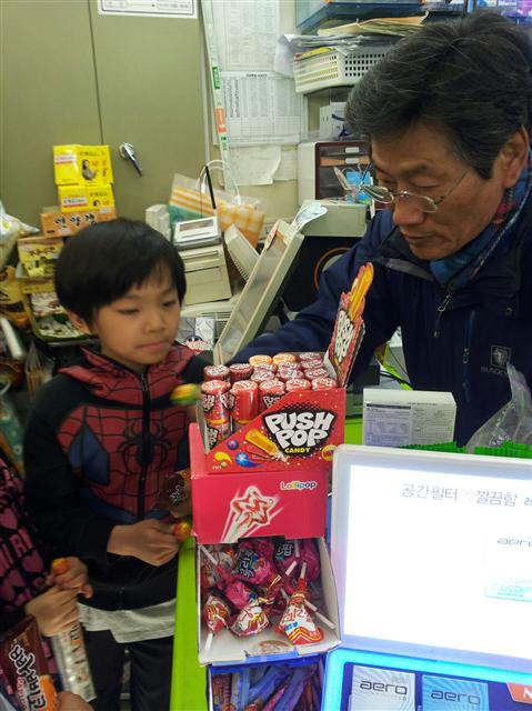 김능환 전 선거관리위원장이 편의점을 찾은 동네 아이들에게 무료로 사탕을 나눠주는 모습.