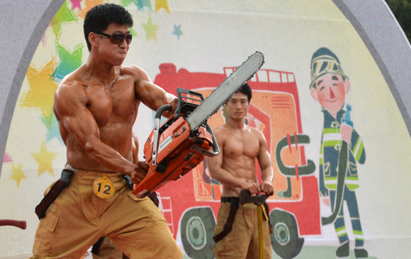 2일 서울 여의도공원 문화광장에서 열린 서울시 최강 몸짱 소방관 선발대회에 참가한 한 소방관이 체인톱을 들고 자유포즈를 취하며 근육을 뽐내고 있다.  