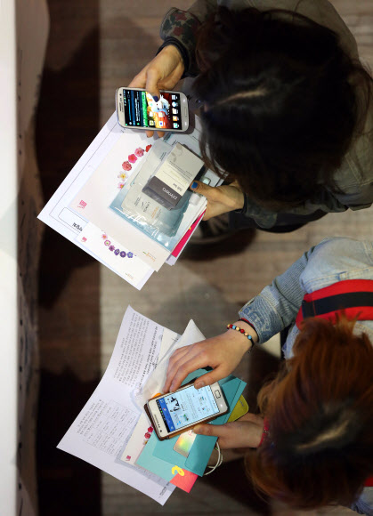 3일 오후 서울 서대문구 이화여대에서 열린 ‘2013 서울시 여대생 일자리박람회’에서 참가자들이 스마트폰을 이용해 한 기업의 정보를 찾고 있다.  연합뉴스