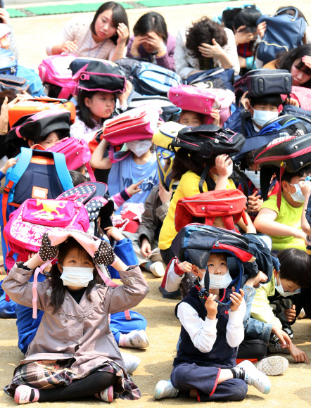 전국적으로 지진대비 민방공훈련이 열린 7일 오후 서울 용산구 효창동 금양초등학교에서 훈련 사이렌이 울리자 학생들이 가방을 머리에 뒤집어 쓴 채 운동장에 앉아있다. 연합뉴스