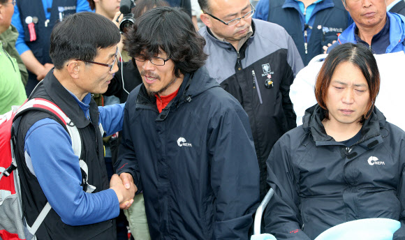 9일 오전 지난해 11월 20일부터 쌍용자동차 정리해고에 관한 국정조사와 해고자 복직 등을 요구하며 쌍용차 평택공장 인근 송전탑에 올라 농성을 벌여온 금속노조 쌍용차지부 한상균 전 지부장(가운데)과 복기성 비정규직 수석부지회장(오른쪽)이 농성을 풀고 송전탑에서 내려온 뒤 동료와 인사를 나누고 있다. 연합뉴스