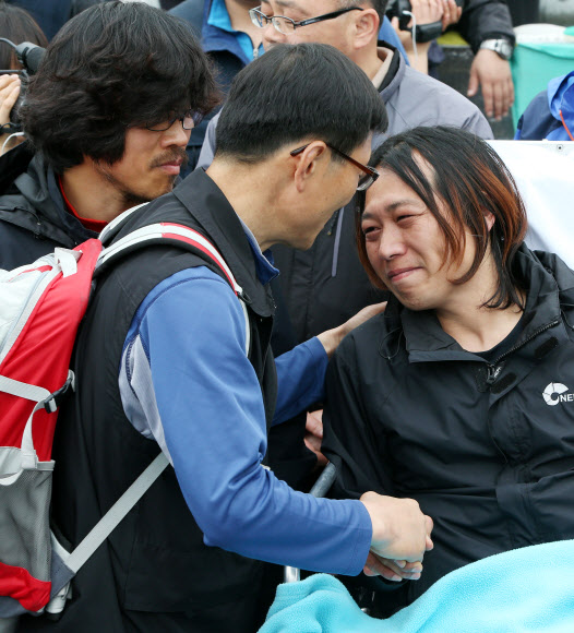 9일 오전 지난해 11월 20일부터 쌍용자동차 정리해고에 관한 국정조사와 해고자 복직 등을 요구하며 쌍용차 평택공장 인근 송전탑에 올라 농성을 벌여온 금속노조 쌍용차지부 한상균 전 지부장(왼쪽)과 복기성 비정규직 수석부지회장(오른쪽)이 농성을 풀고 송전탑에서 내려온 뒤 동료와 인사를 나누고 있다. 연합뉴스