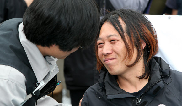 9일 오전 지난해 11월 20일부터 쌍용자동차 정리해고에 관한 국정조사와 해고자 복직 등을 요구하며 쌍용차 평택공장 인근 송전탑에 올라 농성을 벌여온 금속노조 쌍용차지부 한상균 전 지부장과 복기성 비정규직 수석부지회장(오른쪽)이 농성을 풀고 송전탑에서 내려온 뒤 동료와 인사를 나누고 있다. 연합뉴스