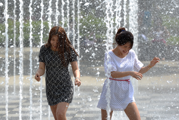 한낮 기온이 27도에 달하며 때이른 더위가 찾아온 13일 서울 성동구 성수동 서울숲 분수대에 들어간 여성들이 갑작스레 솟아오른 물줄기에 놀라 뛰어나고 있다. 손형준 boltagoo@seoul.co.kr