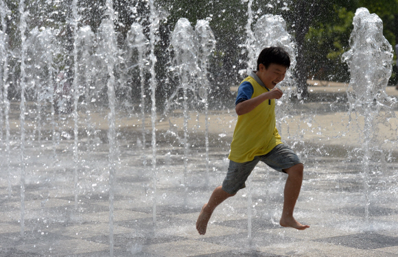 한낮 기온이 27도에 달하며 때이른 더위가 찾아온 13일 서울 성동구 성수동 서울숲 분수대에서 한 어린이가 솟아오르는 물줄기 사이에서 장난치며 더위를 식히고 있다. 손형준 boltagoo@seoul.co.kr
