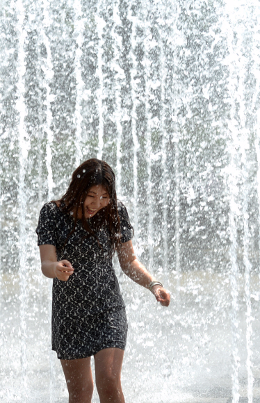 한낮 기온이 27도에 달하며 때이른 더위가 찾아온 13일 서울 성동구 성수동 서울숲 분수대에 들어간 여성들이 갑작스레 솟아오른 물줄기에 놀라 뛰어나고 있다. 손형준 boltagoo@seoul.co.kr