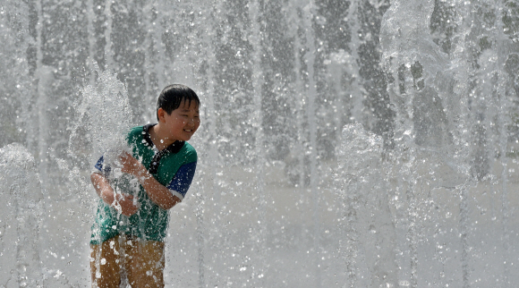한낮 기온이 27도에 달하며 때이른 더위가 찾아온 13일 서울 성동구 성수동 서울숲 분수대에서 한 어린이가 솟아오르는 물줄기 사이에서 장난치며 더위를 식히고 있다. 손형준 boltagoo@seoul.co.kr