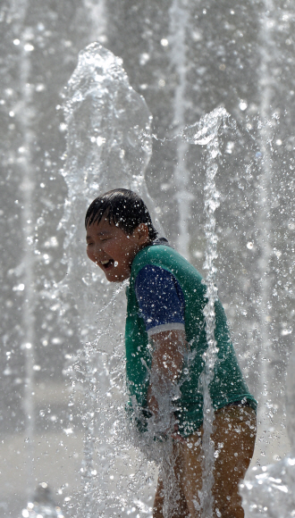 한낮 기온이 27도에 달하며 때이른 더위가 찾아온 13일 서울 성동구 성수동 서울숲 분수대에서 한 어린이가 솟아오르는 물줄기 사이에서 장난치며 더위를 식히고 있다. 손형준 boltagoo@seoul.co.kr