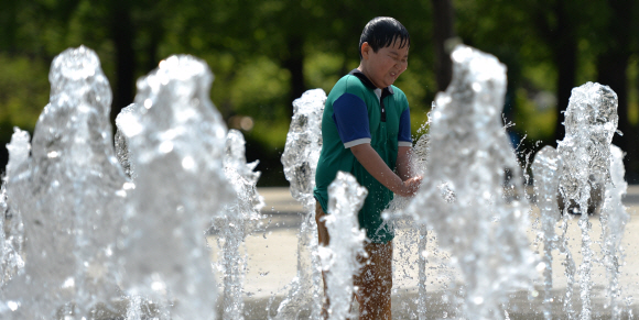 한낮 기온이 27도에 달하며 때이른 더위가 찾아온 13일 서울 성동구 성수동 서울숲 분수대에서 한 어린이가 솟아오르는 물줄기 사이에서 장난치며 더위를 식히고 있다. 손형준 boltagoo@seoul.co.kr
