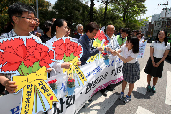 15일 오전 서울 종로구 서울특별시교육청 앞에서 열린 ‘민주ㆍ양심교사 조연희,박정훈,이형빈 선생님 복직촉구’ 기자회견에서 한 학생이 이형빈 씨에게 카네이션을 전달하는 퍼포먼스를 선보이고 있다.  연합뉴스