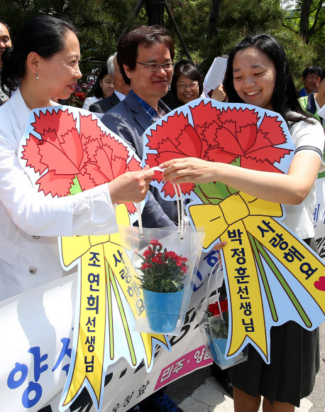 15일 오전 서울 종로구 서울특별시교육청 앞에서 열린 ‘민주ㆍ양심교사 조연희,박정훈,이형빈 선생님 복직촉구’ 기자회견에서 한 학생이 조연희 씨에게 카네이션을 전달하는 퍼포먼스를 선보이고 있다. 연합뉴스
