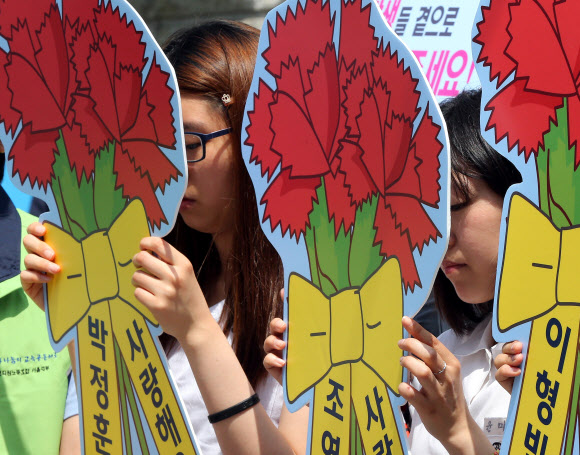 15일 오전 서울 종로구 서울특별시교육청 앞에서 열린 ‘민주ㆍ양심교사 조연희,박정훈,이형빈 선생님 복직촉구’ 기자회견에서 학생들이 굳은 표정으로 카네이션 팻말을 들고 서있다.  연합뉴스