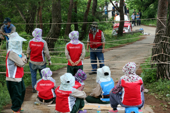 20일 한전이 경남 밀양지역 765㎸ 송전탑 공사를 재개한 가운데 공사현장인 시내 부북면 위양리 평밭마을 입구에 공사에 반대하는 마을 주민들이 한전, 경찰 측과 먼 거리에서 대치하고 있다.반대 주민들은 나무와 나무 사이를 로프로 연결하고 경운기 등으로 바리케이드를 치고 곳곳에 목줄을 설치하는 등 강경하게 반발하고 있다.