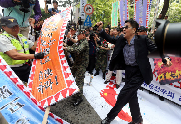 주한일본대사관 앞에 모인 대한민국고엽제전우회 등 보수단체 회원들이 아베 일본 총리와 하시모토 오사카 시장의 얼굴이 인쇄된 현수막을 불태우려 하자 경찰이 이를 빼앗고 있다. 연합뉴스