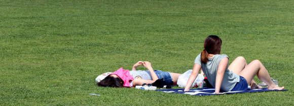 서울의 기온이 30도까지 올라간 23일 오후 서울광장에서 시민이 일광욕을 즐기고 있다.  연합뉴스